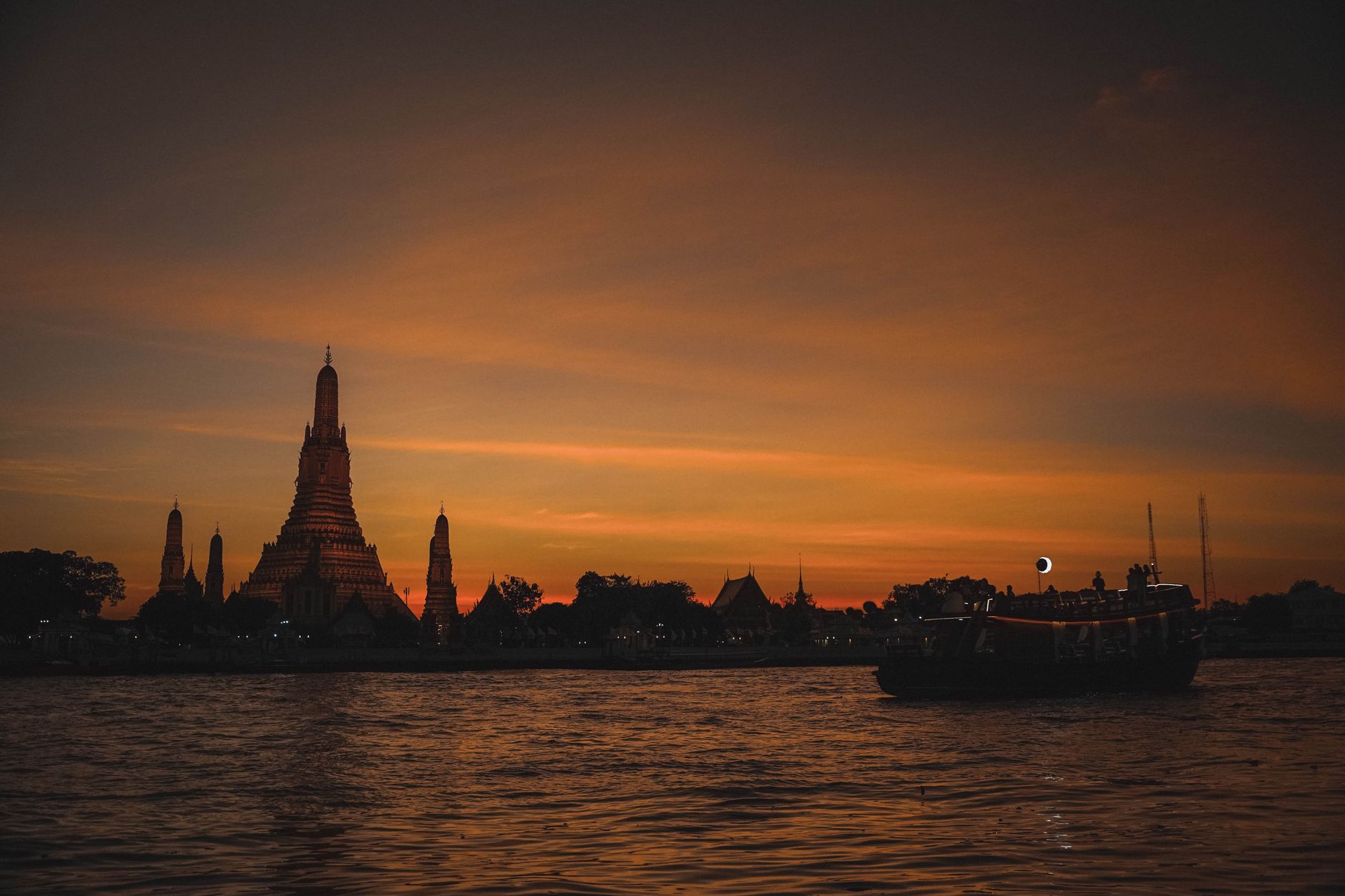 Wat Arun silhouetted against the sunset above the Chao Phraya River in Bangkok
